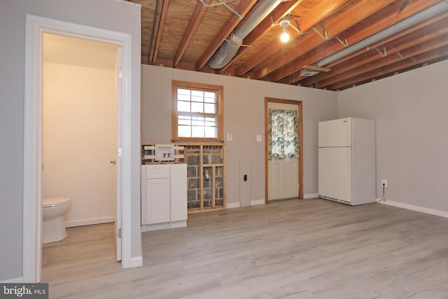 basement featuring white refrigerator and light hardwood / wood-style floors