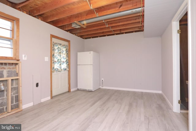 basement with white fridge and light hardwood / wood-style flooring