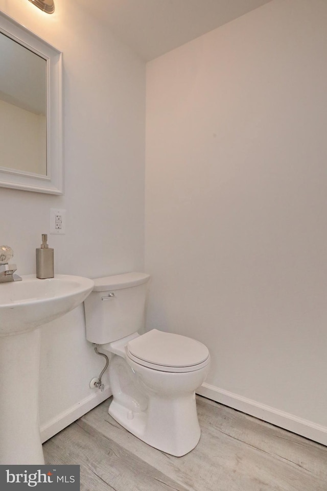 bathroom with toilet, hardwood / wood-style floors, and sink