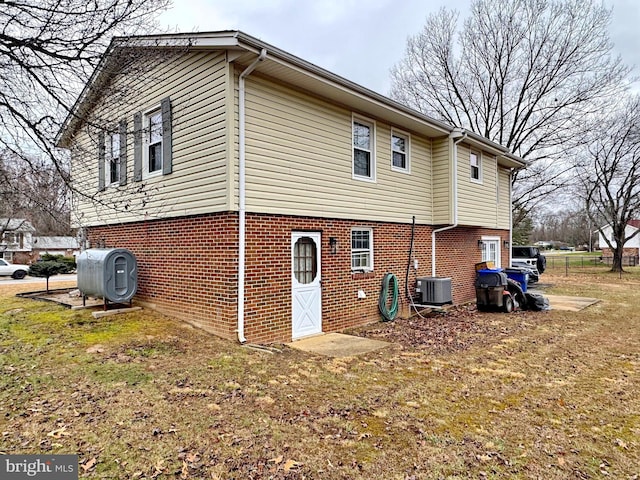 rear view of property with a yard and central air condition unit