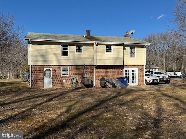 rear view of property featuring central AC unit, a lawn, and french doors