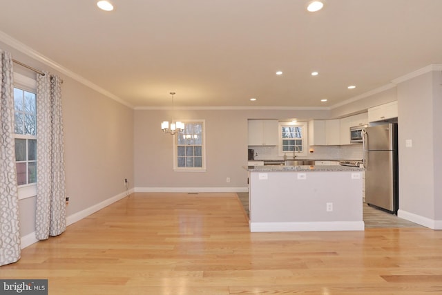 kitchen with hanging light fixtures, stainless steel appliances, white cabinets, and a kitchen island