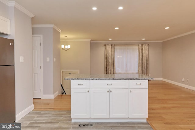 kitchen featuring light stone countertops, white cabinets, stainless steel fridge, and light hardwood / wood-style flooring