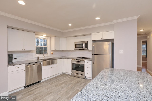 kitchen featuring light stone counters, backsplash, white cabinetry, and stainless steel appliances