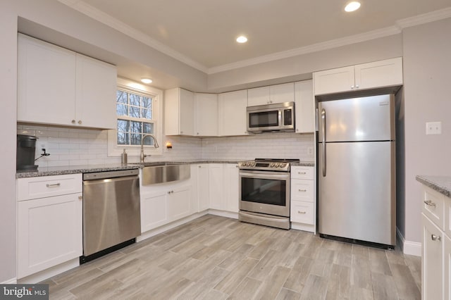 kitchen featuring appliances with stainless steel finishes, white cabinetry, decorative backsplash, sink, and stone countertops