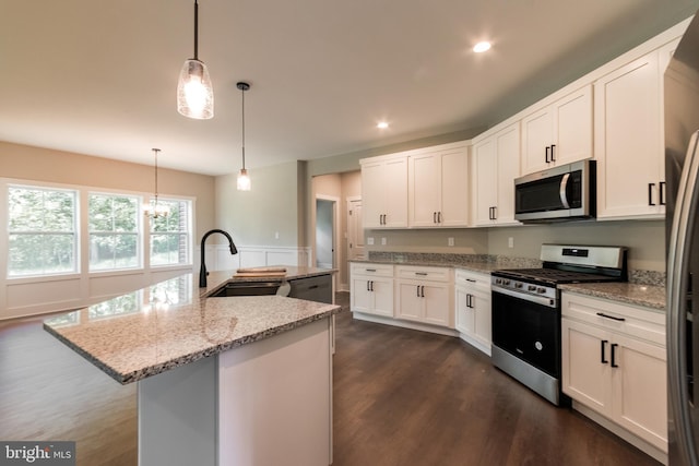 kitchen with white cabinetry, sink, light stone countertops, a center island with sink, and appliances with stainless steel finishes