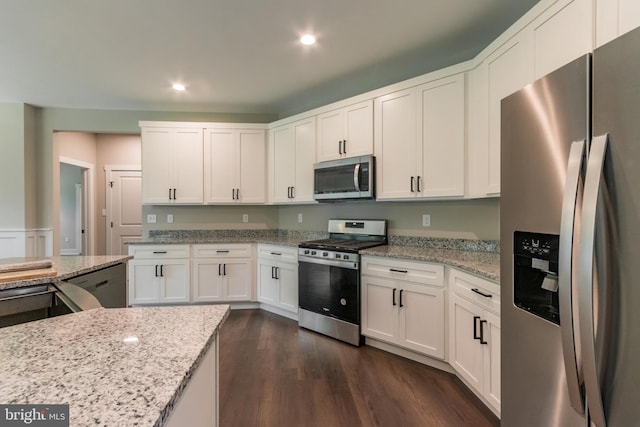 kitchen featuring light stone countertops, white cabinetry, dark wood-type flooring, and appliances with stainless steel finishes