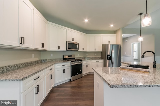 kitchen featuring sink, dark hardwood / wood-style floors, pendant lighting, white cabinets, and appliances with stainless steel finishes