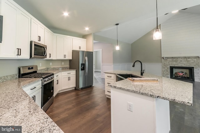 kitchen featuring white cabinetry, stainless steel appliances, dark hardwood / wood-style floors, pendant lighting, and vaulted ceiling