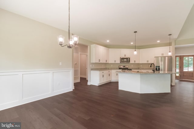 kitchen with white cabinetry, dark wood-type flooring, light stone counters, an island with sink, and appliances with stainless steel finishes