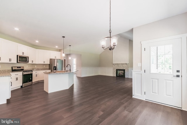 kitchen with a center island with sink, decorative light fixtures, white cabinets, and stainless steel appliances