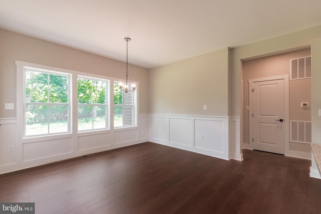 spare room featuring dark hardwood / wood-style flooring and an inviting chandelier