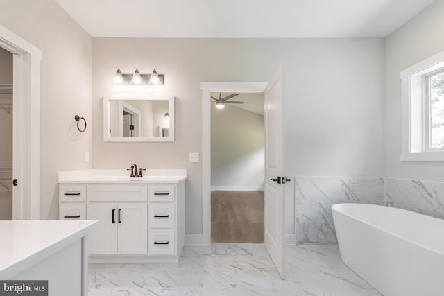 bathroom with vanity, a tub to relax in, ceiling fan, and tile walls