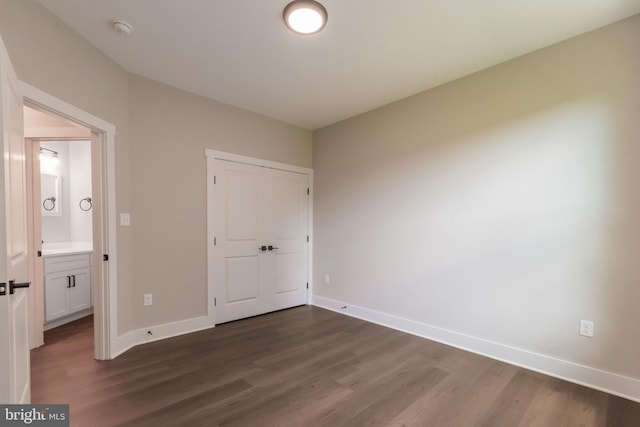 unfurnished bedroom featuring dark hardwood / wood-style flooring and ensuite bath