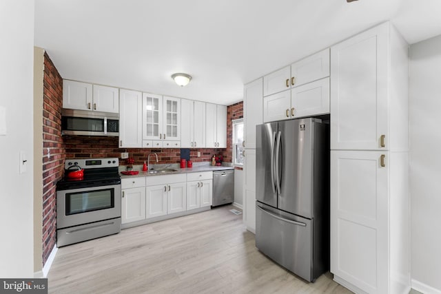 kitchen with stainless steel appliances, white cabinetry, tasteful backsplash, and light hardwood / wood-style floors