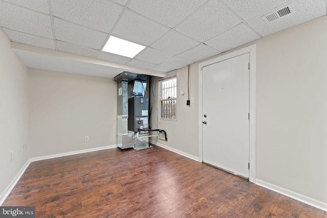 interior space featuring a paneled ceiling, dark hardwood / wood-style floors, and heating unit