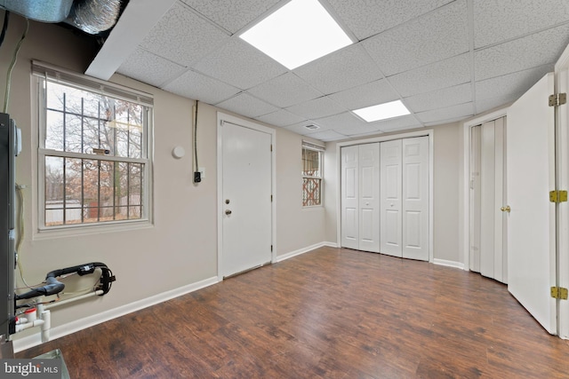 basement featuring a paneled ceiling and dark wood-type flooring