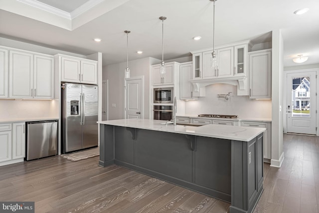 kitchen with a kitchen island with sink, stainless steel appliances, dark hardwood / wood-style floors, white cabinetry, and decorative light fixtures