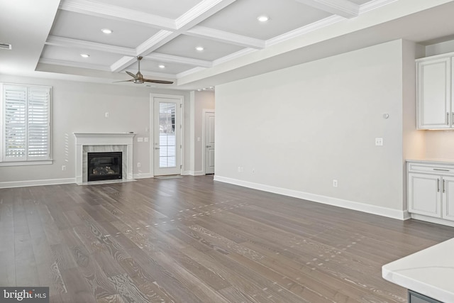 unfurnished living room featuring a premium fireplace, hardwood / wood-style floors, beam ceiling, ceiling fan, and coffered ceiling