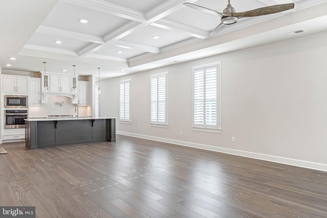 kitchen with stainless steel oven, decorative light fixtures, a large island with sink, white cabinets, and black microwave