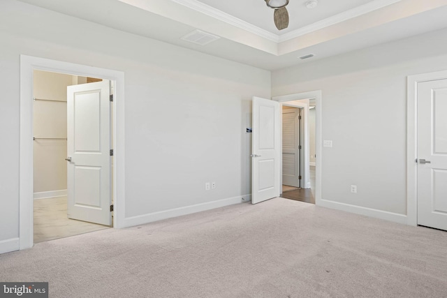 unfurnished bedroom with a raised ceiling, light carpet, ceiling fan, and ornamental molding