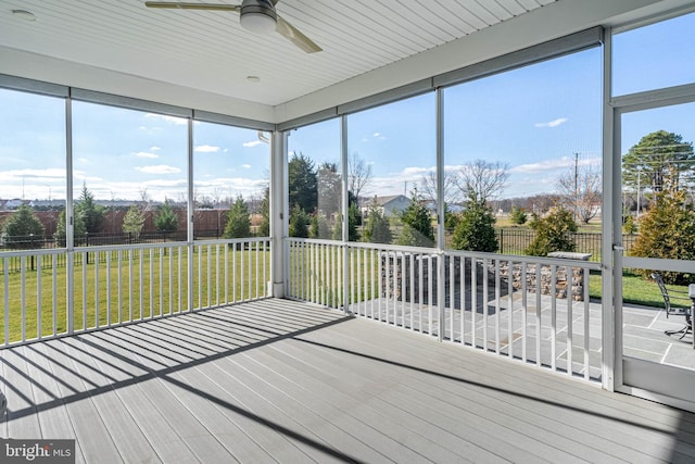 unfurnished sunroom featuring ceiling fan and plenty of natural light