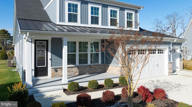 view of front of property with covered porch, central AC unit, and a garage