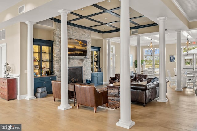 living room featuring a fireplace, an inviting chandelier, light hardwood / wood-style floors, and coffered ceiling