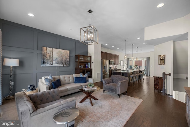 living room featuring sink, dark wood-type flooring, and an inviting chandelier