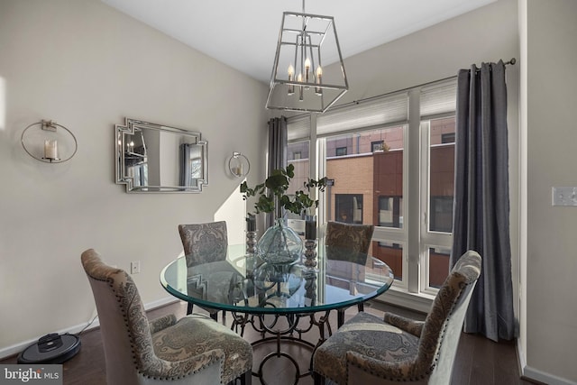 dining area with dark hardwood / wood-style flooring and an inviting chandelier