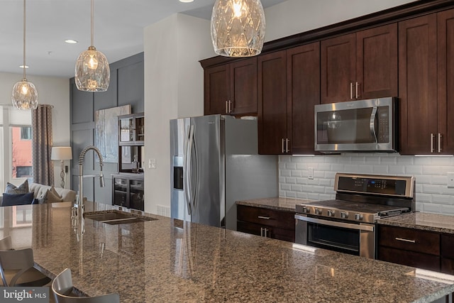 kitchen with pendant lighting, tasteful backsplash, appliances with stainless steel finishes, and dark stone counters