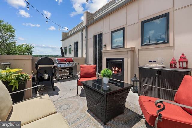 view of patio with an outdoor living space with a fireplace and a grill