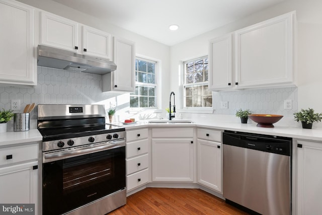 kitchen with sink, white cabinetry, tasteful backsplash, light hardwood / wood-style flooring, and appliances with stainless steel finishes