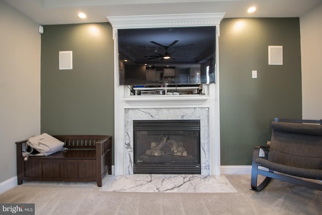 carpeted living room with a fireplace and ceiling fan