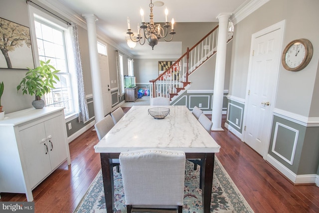 dining space featuring decorative columns, dark hardwood / wood-style flooring, an inviting chandelier, and ornamental molding