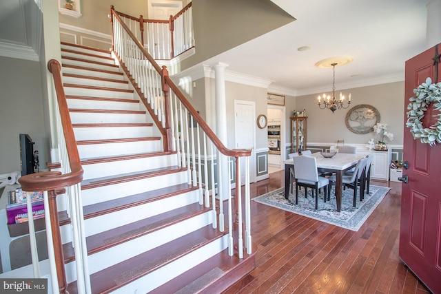 interior space with hardwood / wood-style floors, an inviting chandelier, ornamental molding, and ornate columns