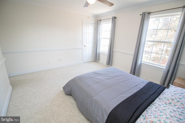 carpeted bedroom featuring ceiling fan and crown molding