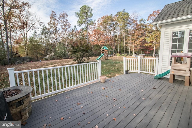 wooden terrace with a playground and a yard