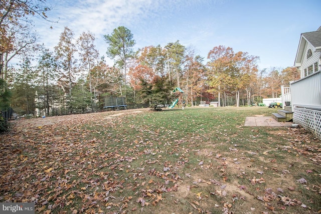 view of yard featuring a playground, a trampoline, and a patio area