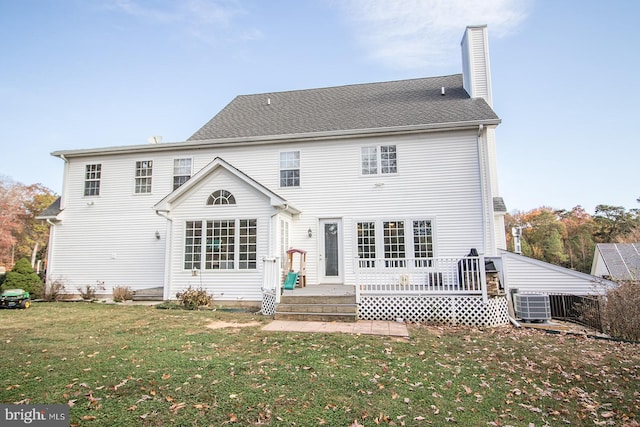 back of property featuring a lawn, a wooden deck, and central AC