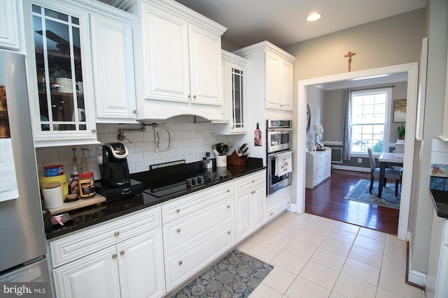 kitchen featuring dark stone countertops, white cabinetry, light hardwood / wood-style floors, and appliances with stainless steel finishes