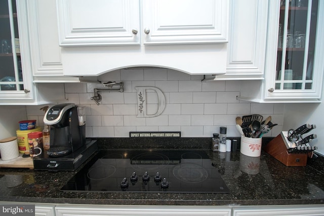 kitchen with backsplash, black electric cooktop, white cabinetry, and dark stone counters