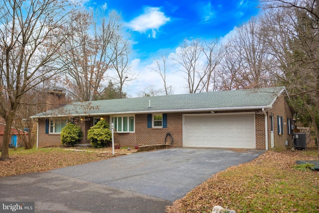 single story home with a garage and central AC unit