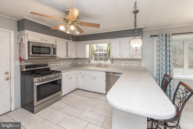 kitchen with white cabinetry, sink, decorative light fixtures, and appliances with stainless steel finishes