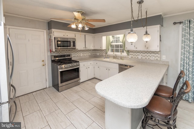 kitchen featuring a kitchen bar, hanging light fixtures, appliances with stainless steel finishes, kitchen peninsula, and white cabinets