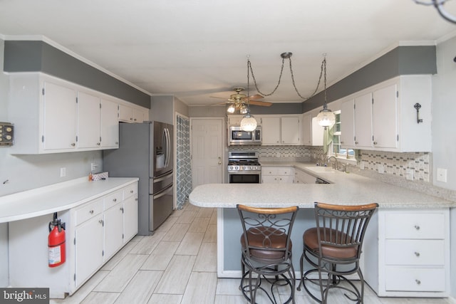 kitchen with white cabinetry, pendant lighting, a breakfast bar, and appliances with stainless steel finishes