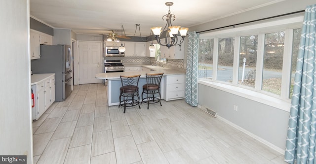 kitchen featuring a breakfast bar area, hanging light fixtures, kitchen peninsula, stainless steel appliances, and white cabinets