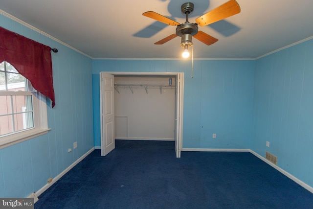 unfurnished bedroom featuring dark carpet, ornamental molding, a closet, and ceiling fan