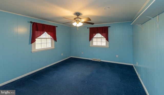 spare room with crown molding, a wealth of natural light, and dark carpet