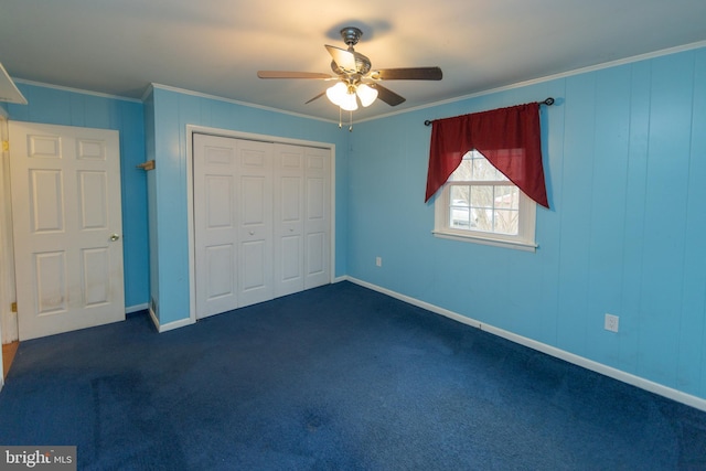 unfurnished bedroom with crown molding, dark carpet, ceiling fan, and a closet